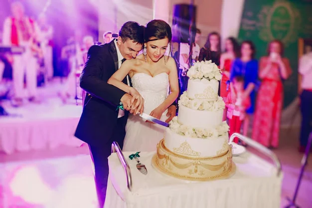 Couples cutting wedding cake in event
